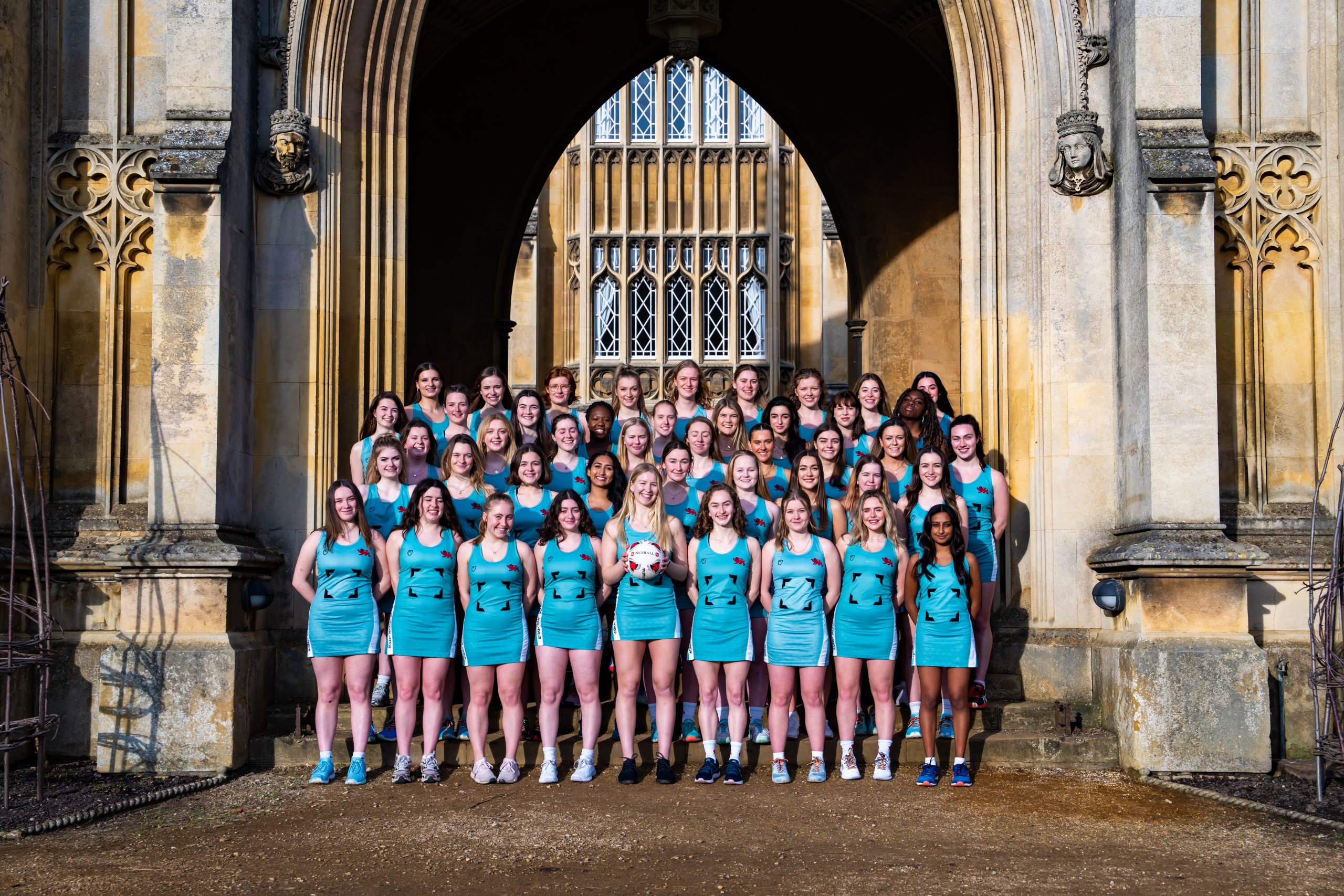 The CULNC club standing with their arms behind their backs in duck egg blue netball dresses, smiling.