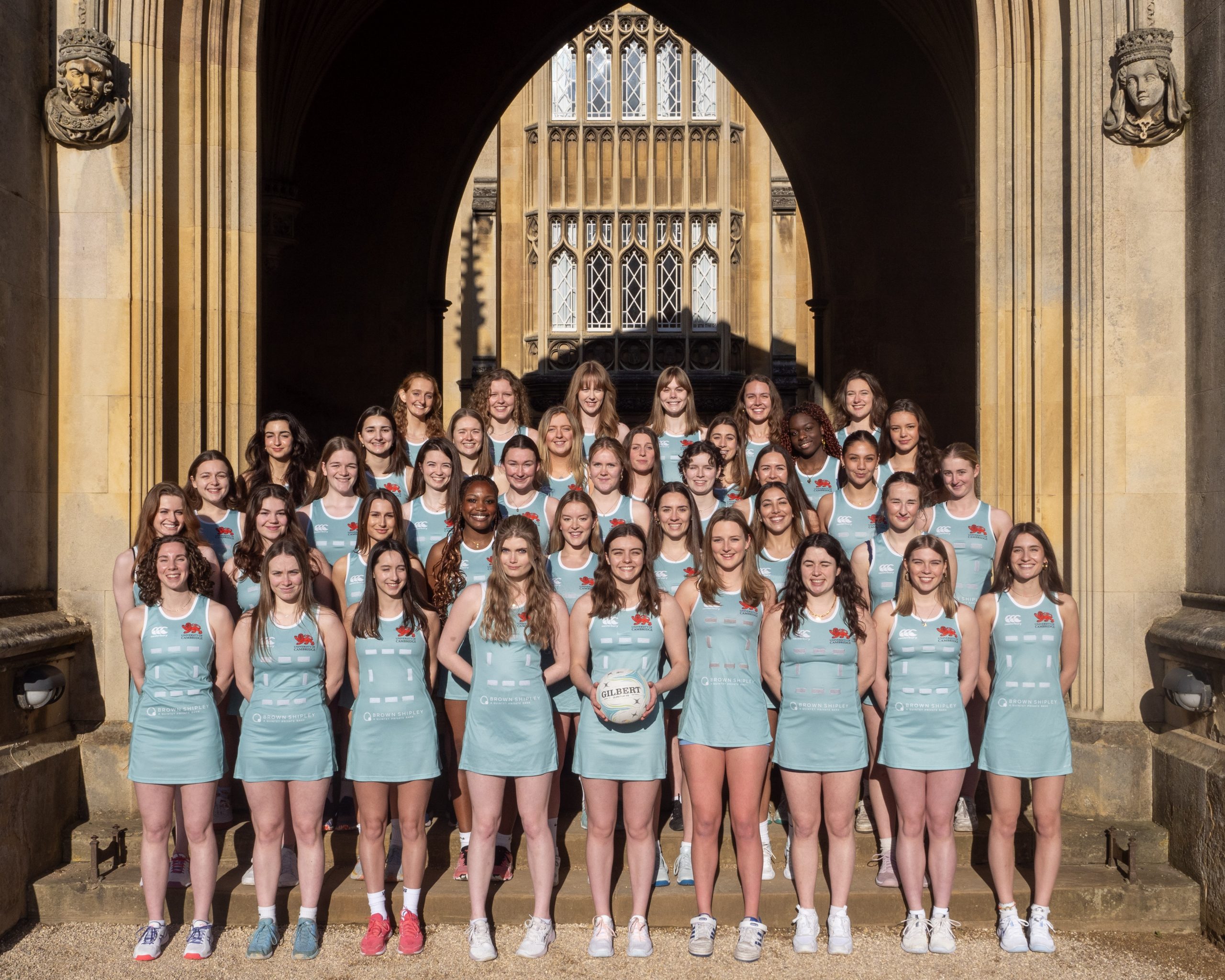 The CULNC club standing with their arms behind their backs in duck egg blue netball dresses, smiling.